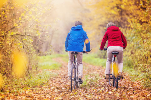 Active seniors riding bike in autumn nature. They relax outdoor.