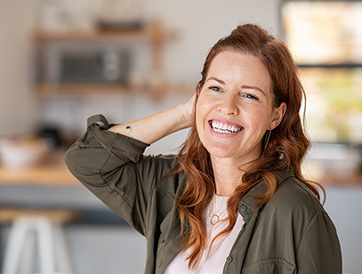 Portrait of beautiful mature woman at home. Successful middle aged woman smiling and looking away while touching hair. Mid redhead lady laughing and relaxing.