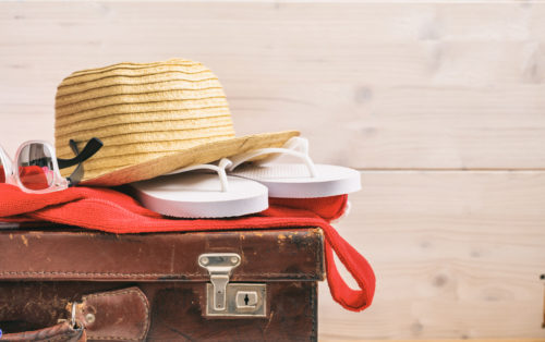 Beach accessories on an old suitcase - white wooden background - copy space