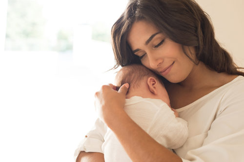 Pretty woman holding a newborn baby in her arms